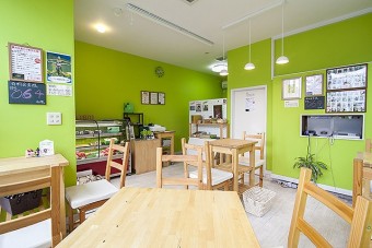 黄緑色の壁と木のテーブルで爽やかな印象の店内